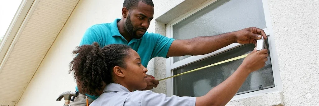 Homeowners measuring window width and height with tape measure on Florida stucco wall