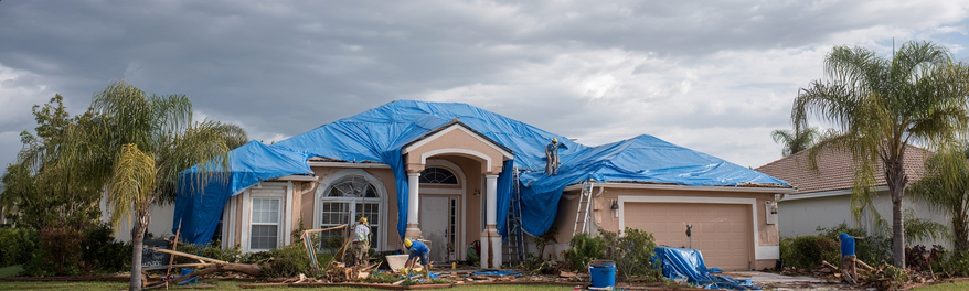 Blue tarp covering Florida stucco home after hurricane